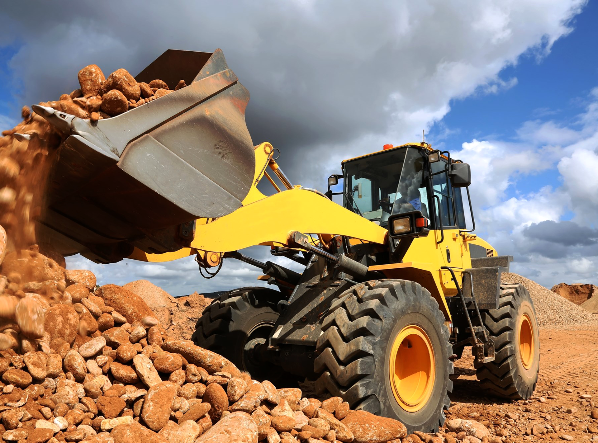 Yellow wheeled loader scooping and lifting construction yard debris